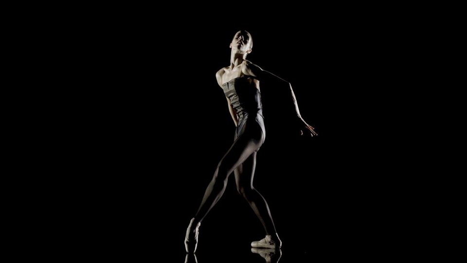 Une danseuse tient une pose de danse contemporaine.