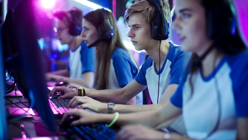Une équipe de deux filles et de deux garçons jouent sur des ordinateurs. 