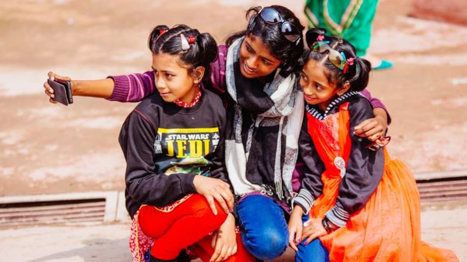 Des filles se photographient en selfie dans une rue de New Delhi.