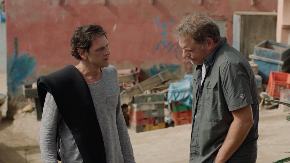 Les deux hommes se parlent dans une cour.