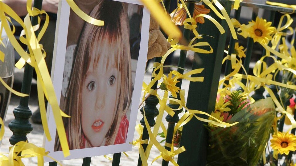 Une photo d'une petite fille accrochée à une barrière avec des fleurs et des rubans.