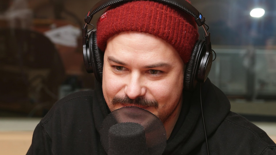 Photo de Marc-André Grondin devant un micro de radio.
