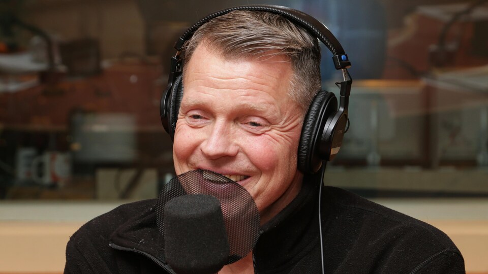 Photo de Mike Finnerty devant un micro de radio.