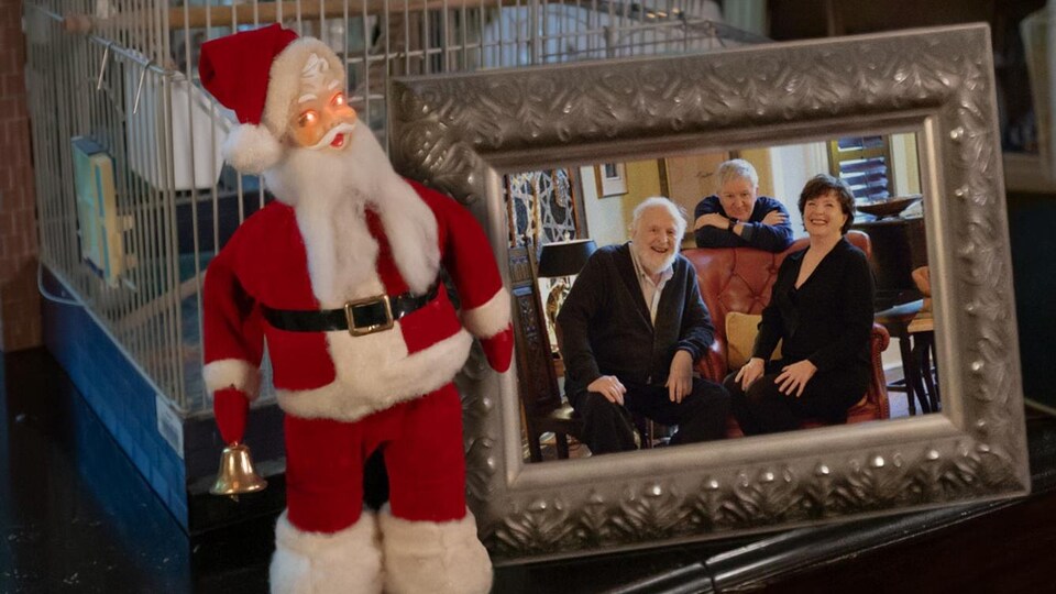 Une photo de famille encadrée repose à côté d'un petit père Noël et d'une cage à oiseaux.