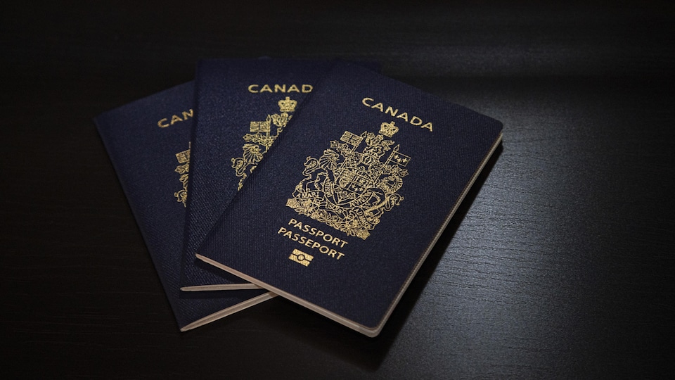 Trois passeports canadiens posés sur une table.