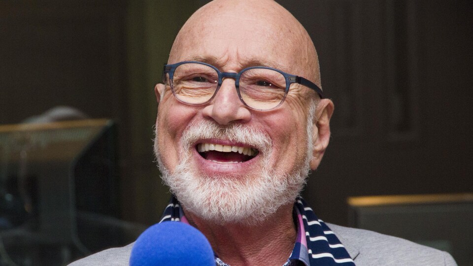 Le chanteur est tout sourire derrière un micro de radio.
