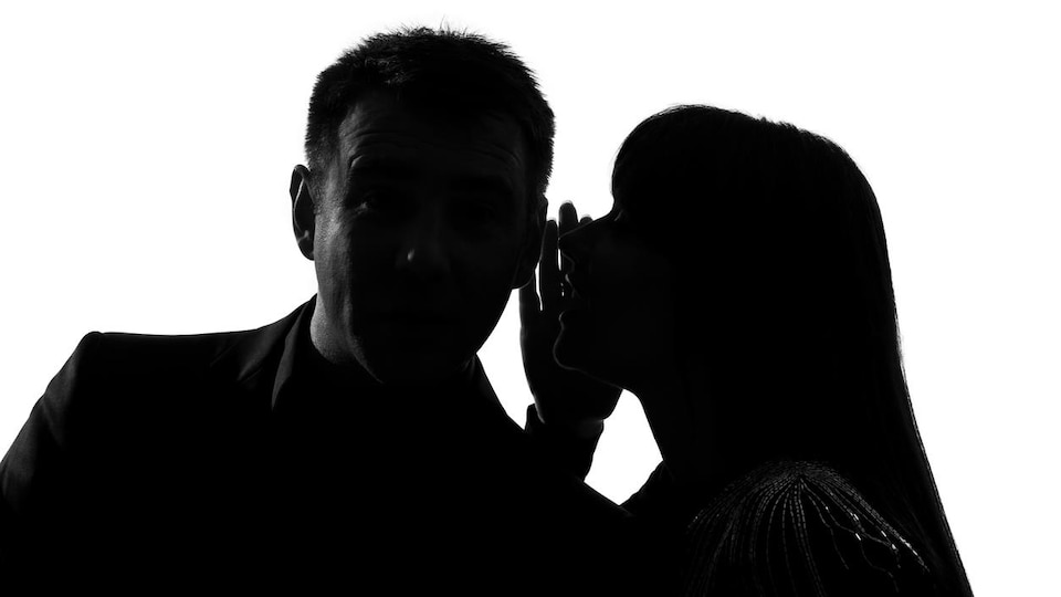 La silhouette d'un homme et d'une femme qui discutent tout bas.