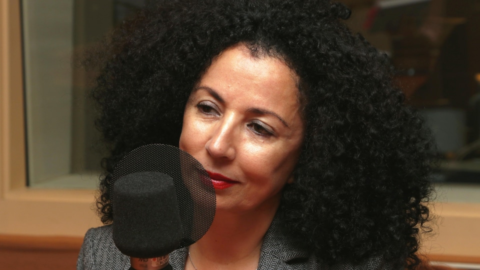 Photo de Rachida Azdouz devant un micro de radio.