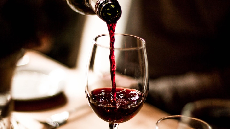 Du vin rouge est versé dans un verre.