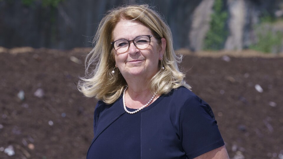 Elle sourit devant un paysage de monticules de terre.