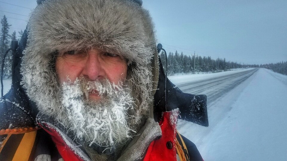 Portrait de Sylvain Paquin dehors devant un paysage enneigé avec la barbe recouverte de neige.
