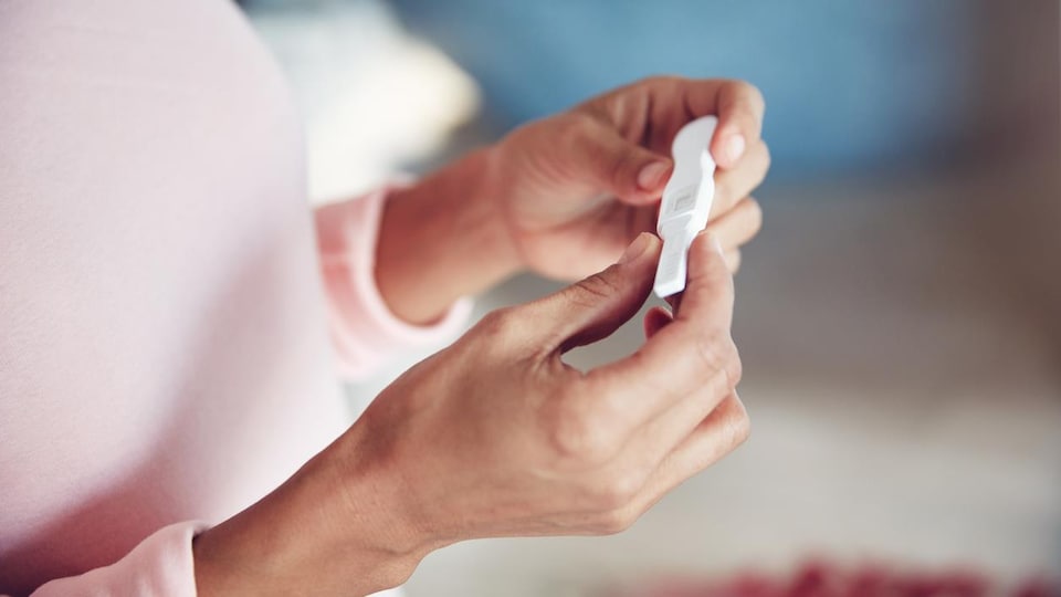 Gros plan d'une femme qui tient un test de grossesse entre les mains. 