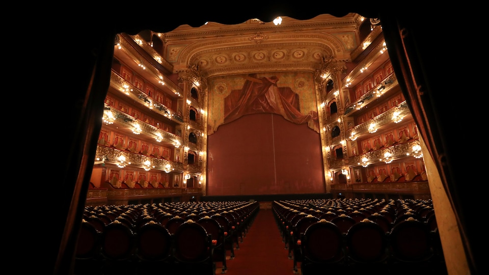 Photo de l'intérieur d'un théâtre dont la décoration mêle le doré et le velours rouge. 
