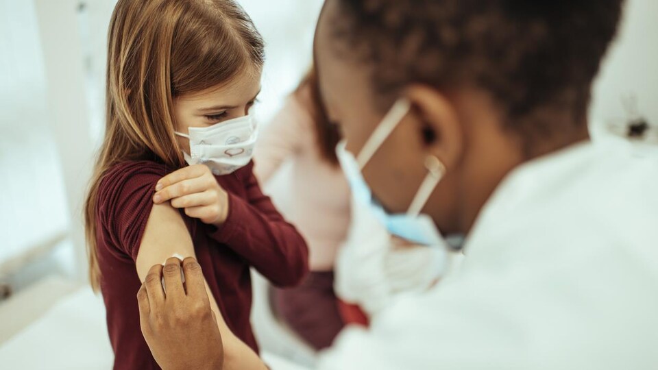 Une infirmière désinfecte le haut du bras d'une fillette.