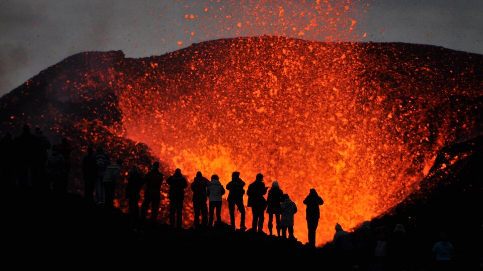 Des silhouettes se dessinent sur fond de volcan en éruption.