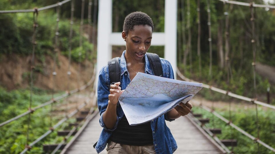 Photo d'une femme qui lit une carte sur un pont dans une forêt.