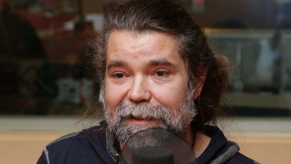 Photo de Yan Défossés devant un micro de radio.