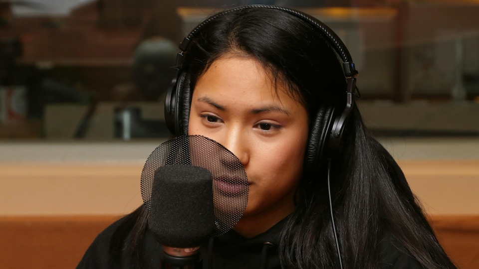Zoé Allaire-Bourgie devant un micro de radio.