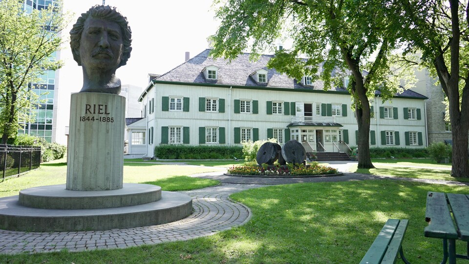 La tête en bronze de Riel trône devant un édifice historique.
