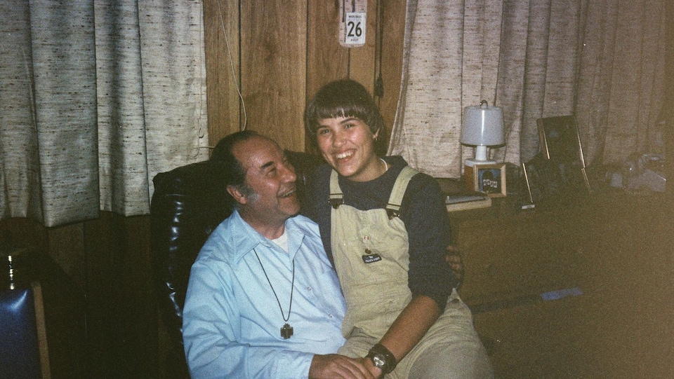 Photo des années 80 montrant Marie-Christine Joveneau assise sur les genoux du père Joveneau.