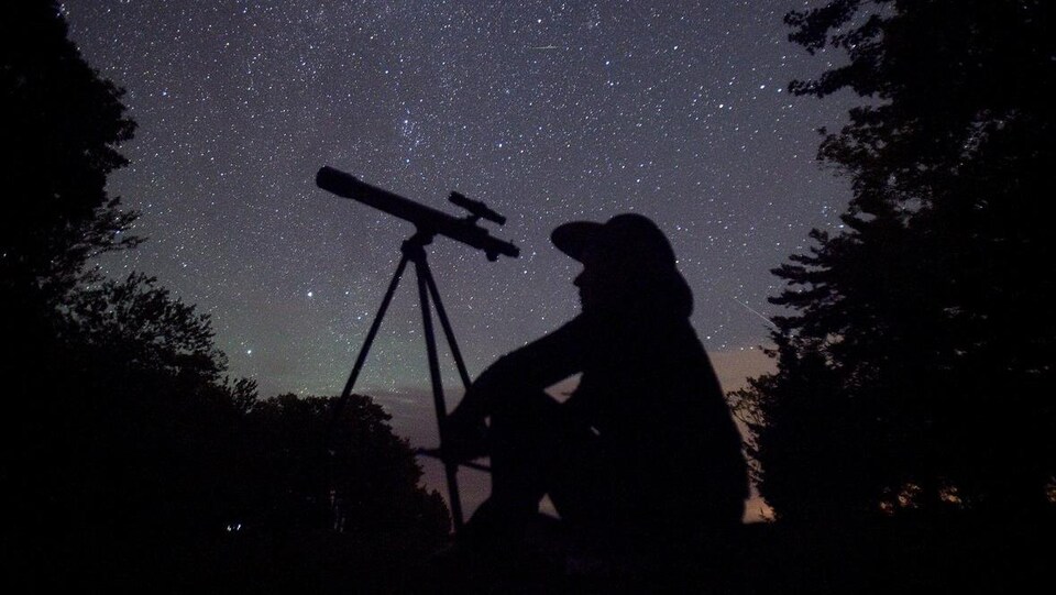 Un astronome amateur avec son télescope.
