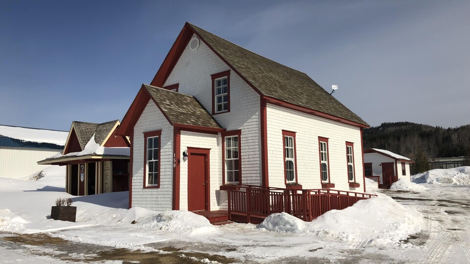 L'école de rang, peinte en blanche et rouge, est bordée de neige