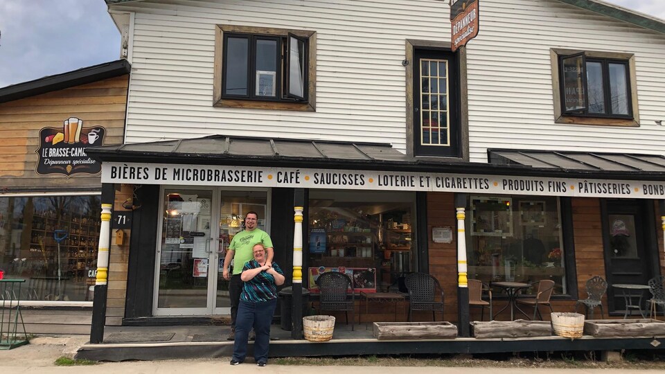 Deux personnes qui posent pour la caméra devant un dépanneur