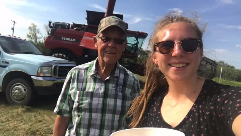 Une fille et son grand-père devant une machine à grain