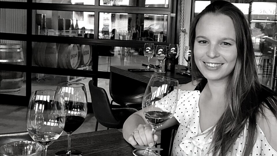Selma Le Gallou attablée dans la salle d'un vignoble, avec des coupes de vin devant elle.