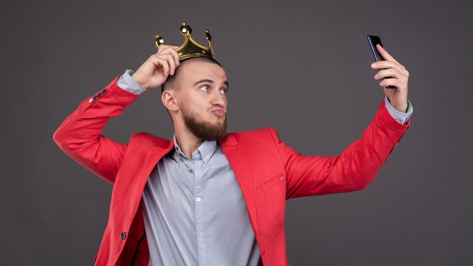 Un homme portant une couronne prend un égoportrait.