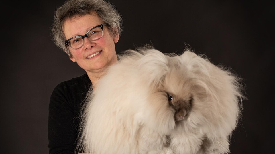 La femme tient un lapin très poilu dans ses mains.