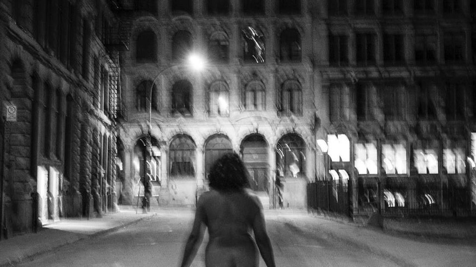 Photo en noir et blanc d'une femme nue dans les rues de Montréal.