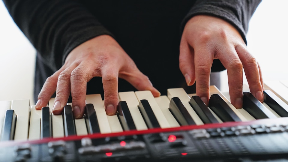 Des mains jouent des notes de musique sur un piano.