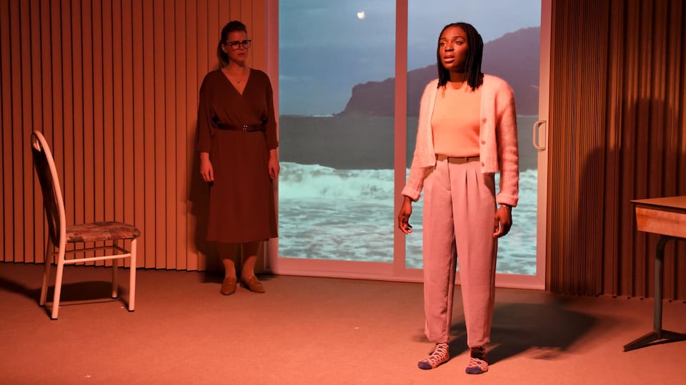 Deux actrices sur une scène de théâtre avec un décor présentant un paysage québécois sur le bord de l'eau. Nous pouvons y voir la lune. 