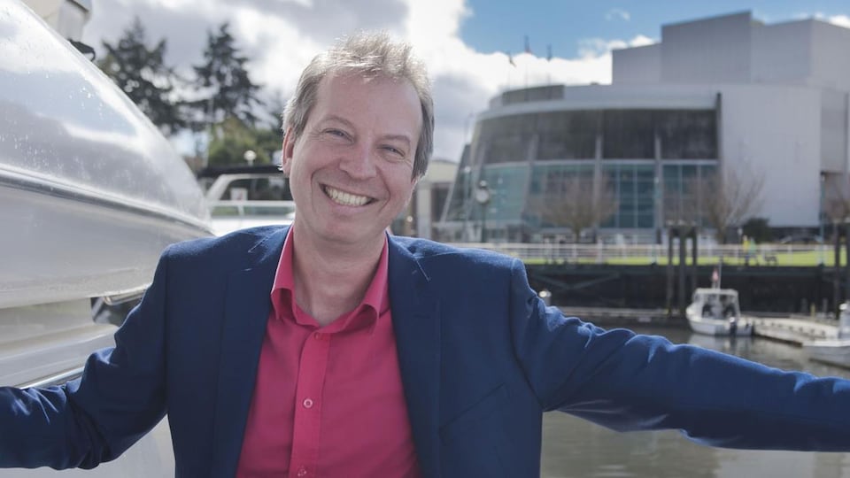 un homme étendant une main face à la caméra, souriant.