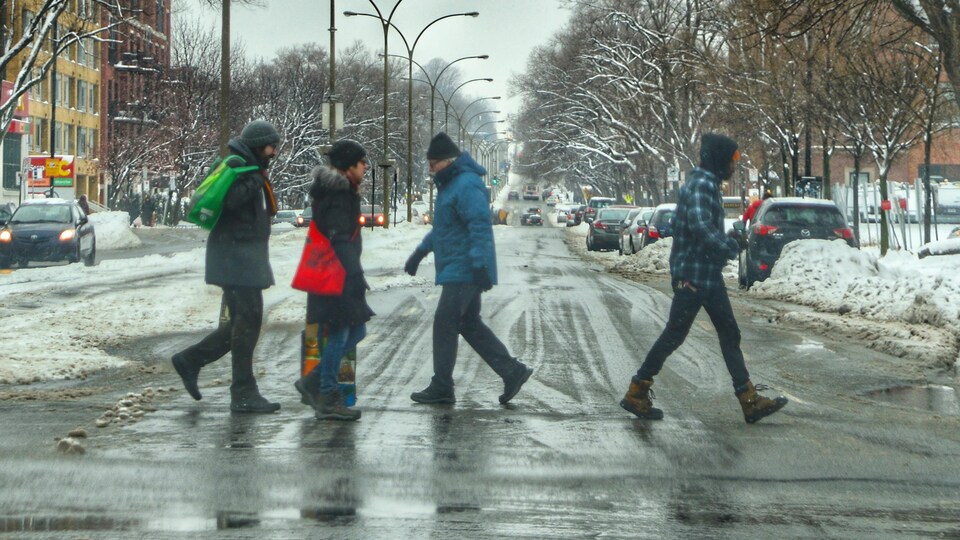 Quatre personnes traversent une rue en hiver.
