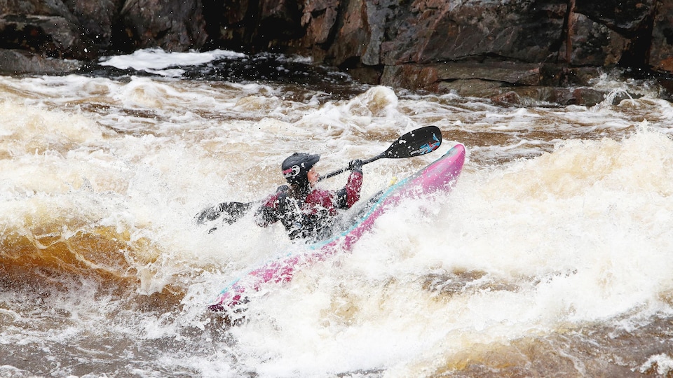 Un femme en kayak dans des rapides.