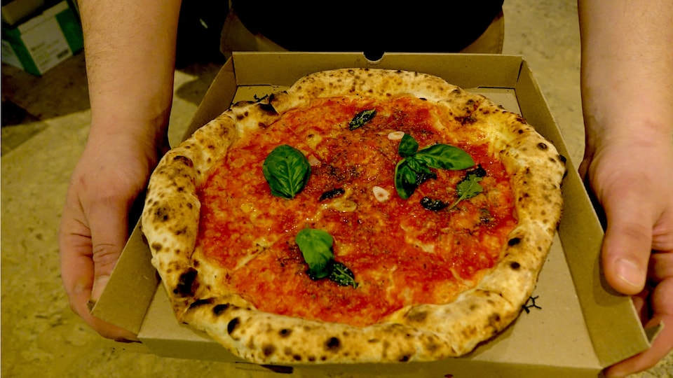Une pizza recouverte de sauce tomate et de feuilles de basilic