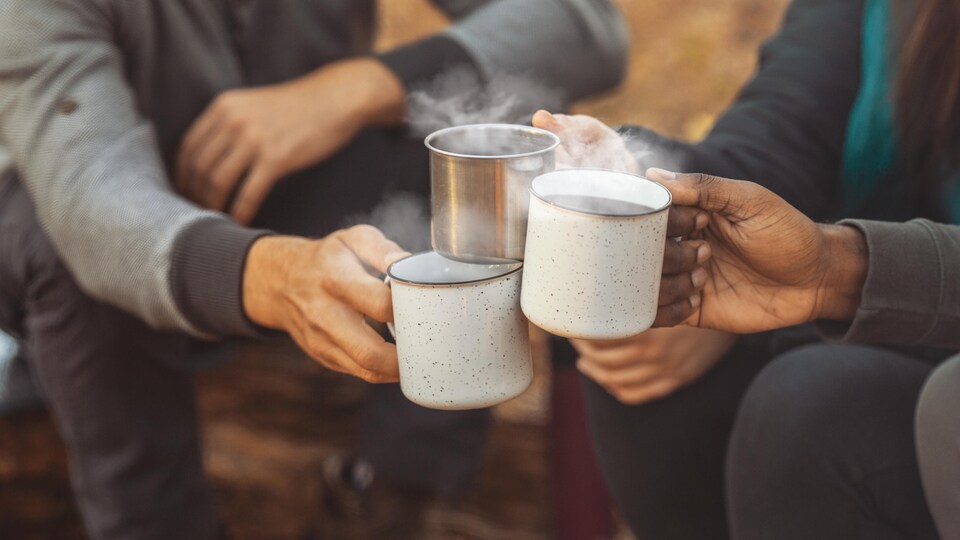 Hands of international hikers cheering up with camping cups, camping in forest, close up