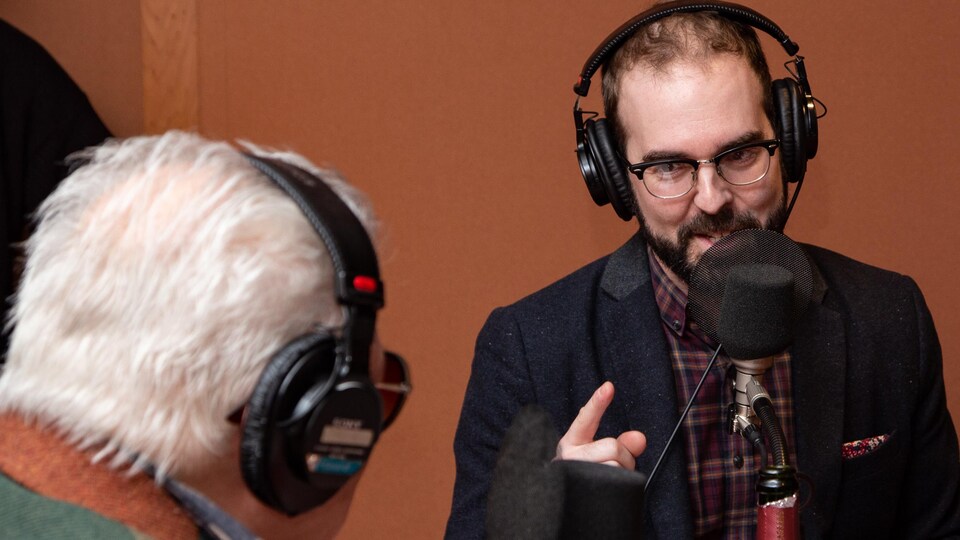 L'auteur barbu à lunettes gesticule en échangeant avec Jean-Paul Daoust.