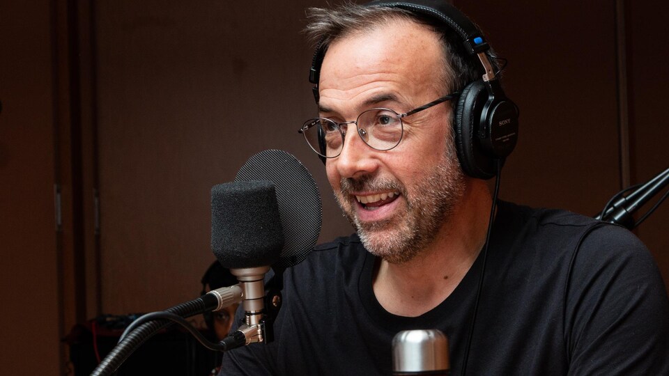 Le comédien à lunettes sourit à l'animatrice.
