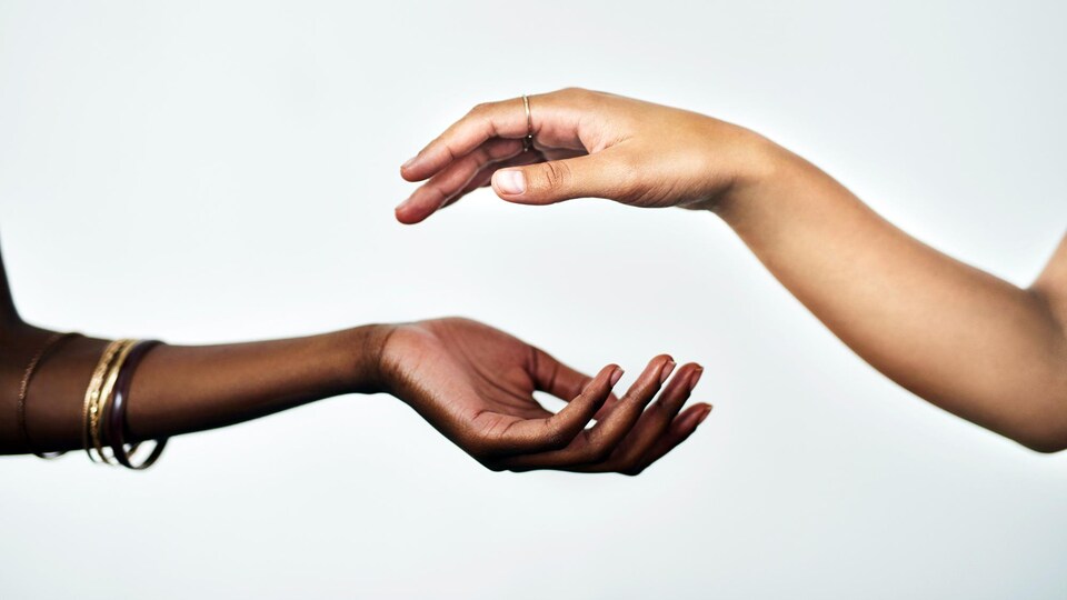 Les mains de deux femmes sont sur le point de se toucher.