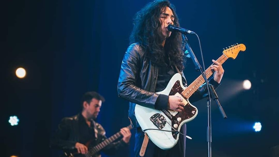 Le chanteur Mateo chante en jouant de la guitare sur scène.