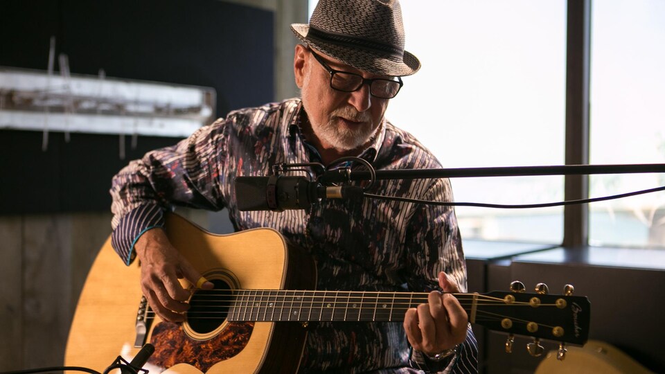 Patrick Norman joue de la guitare dans un studio de radio.