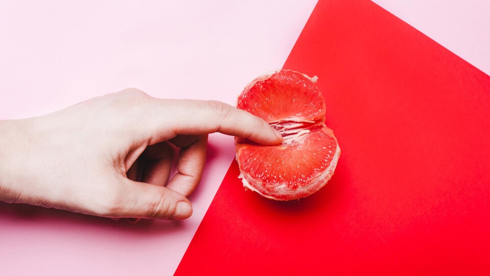 Image conceptuelle d'un doigt dans un quartier d'orange, afin de représenter la sexualité féminine.