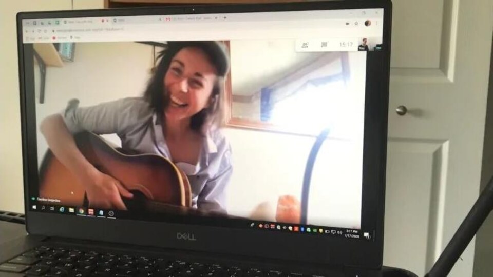 Caroline Allatt est a l'écran d'un ordinateur avec sa guitare.