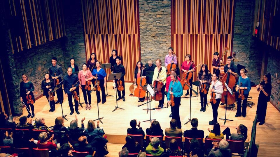 Un orchestre de chambre à cordes reçoit les applaudissements du public.