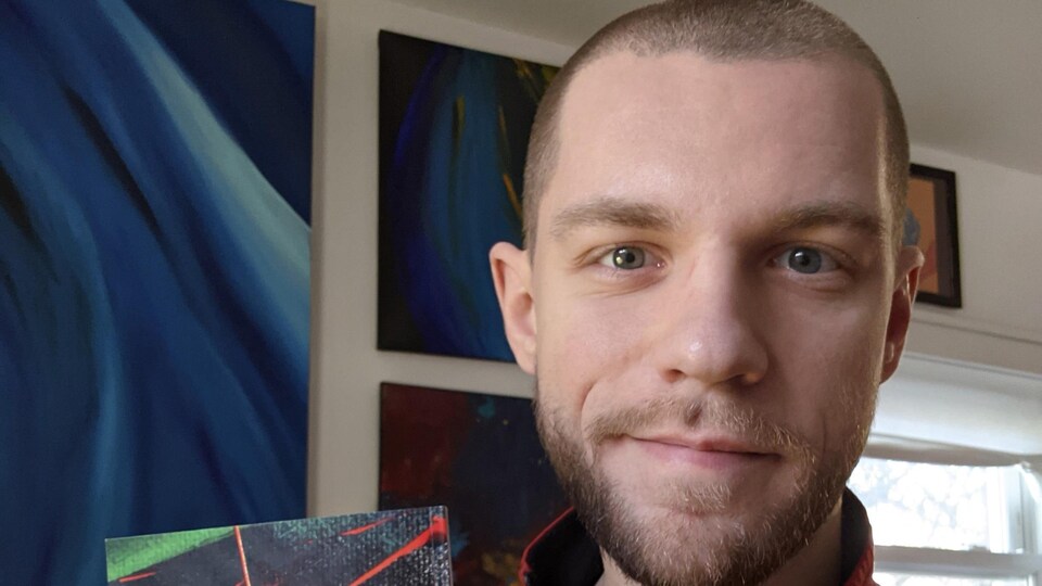 Un homme barbu qui tient un livre de poème.
