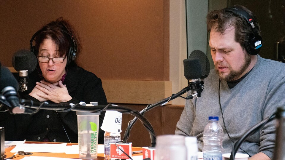 Une femme et un homme lisent un texte dans un studio de radio.