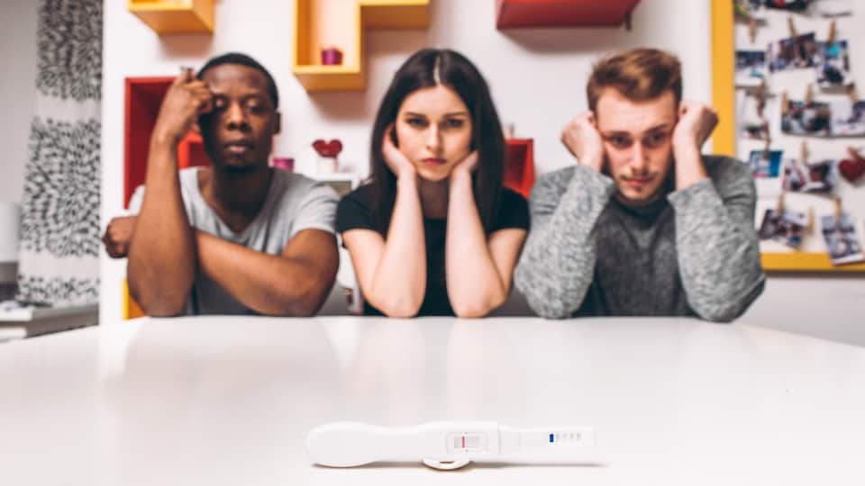 Un groupe de trois parents devant un test de grossesse.